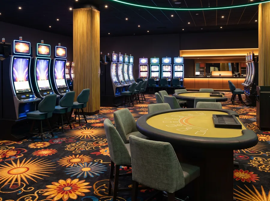 Empty live tables beside slot machines on a patterned carpet